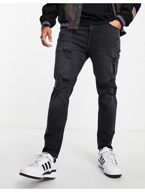 Asos Design tapered jeans in washed black with heavy rips