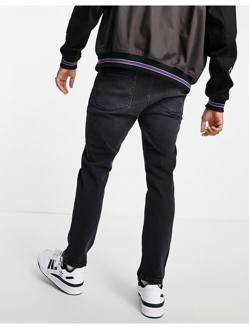 Asos Design tapered jeans in washed black with heavy rips