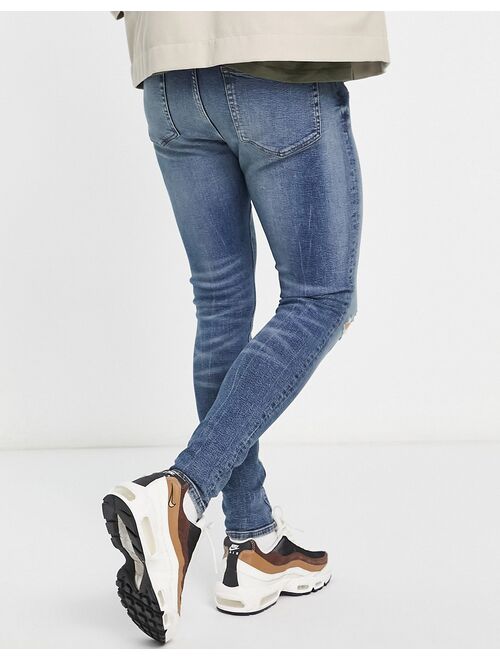 ASOS DESIGN spray on jeans with power stretch in mid wash blue with tint and abrasions