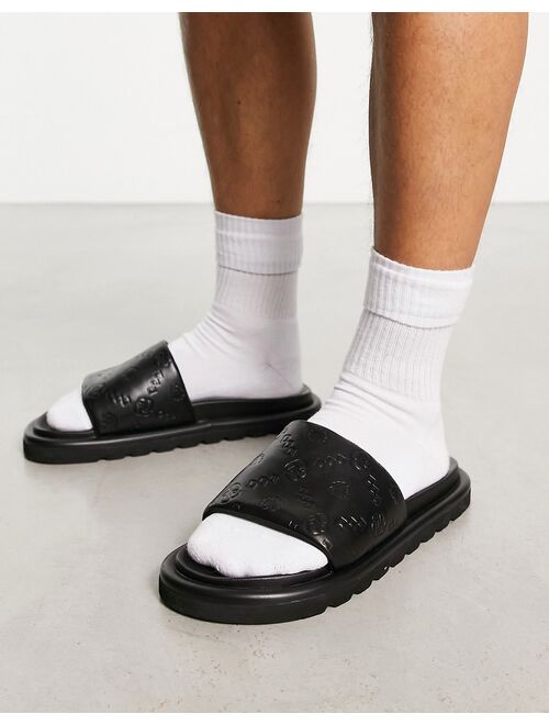 ASOS DESIGN sliders in black faux Leather with monogram emboss