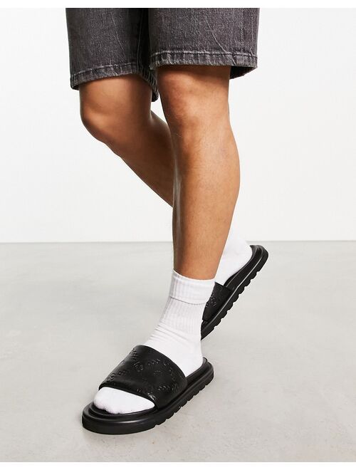 ASOS DESIGN sliders in black faux Leather with monogram emboss