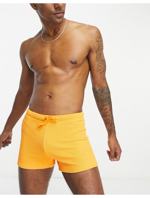 ASOS DESIGN textured swim trunks in orange