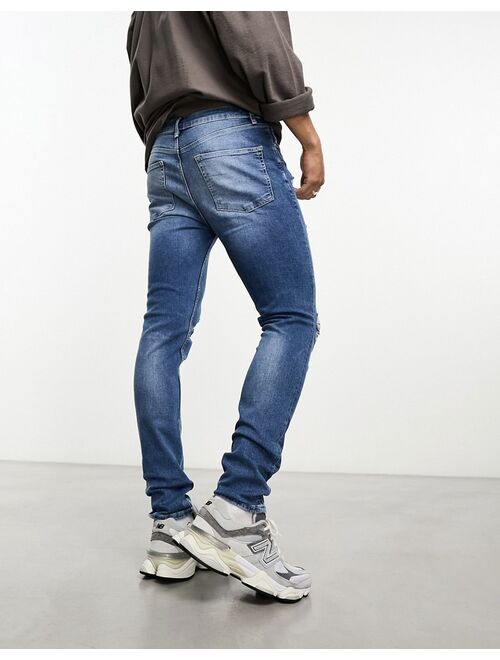 ASOS DESIGN skinny jeans with rips in mid wash blue