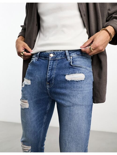 ASOS DESIGN skinny jeans with rips in mid wash blue